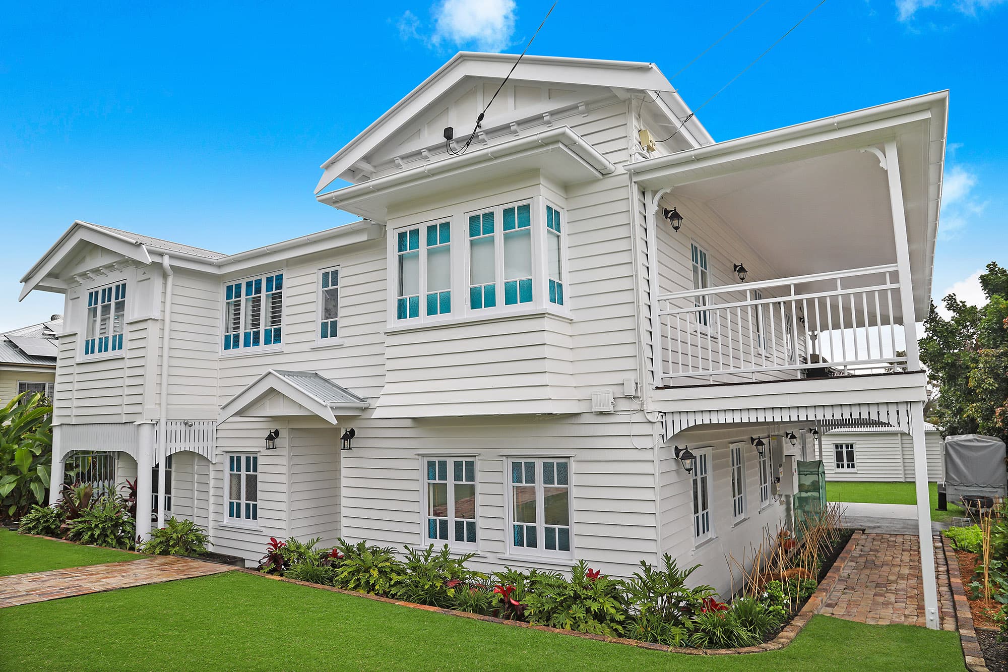 Repainted white weatherboard interwar home in Cannon Hill with gabled roofline, leadlight casement windows and an upper verandah
